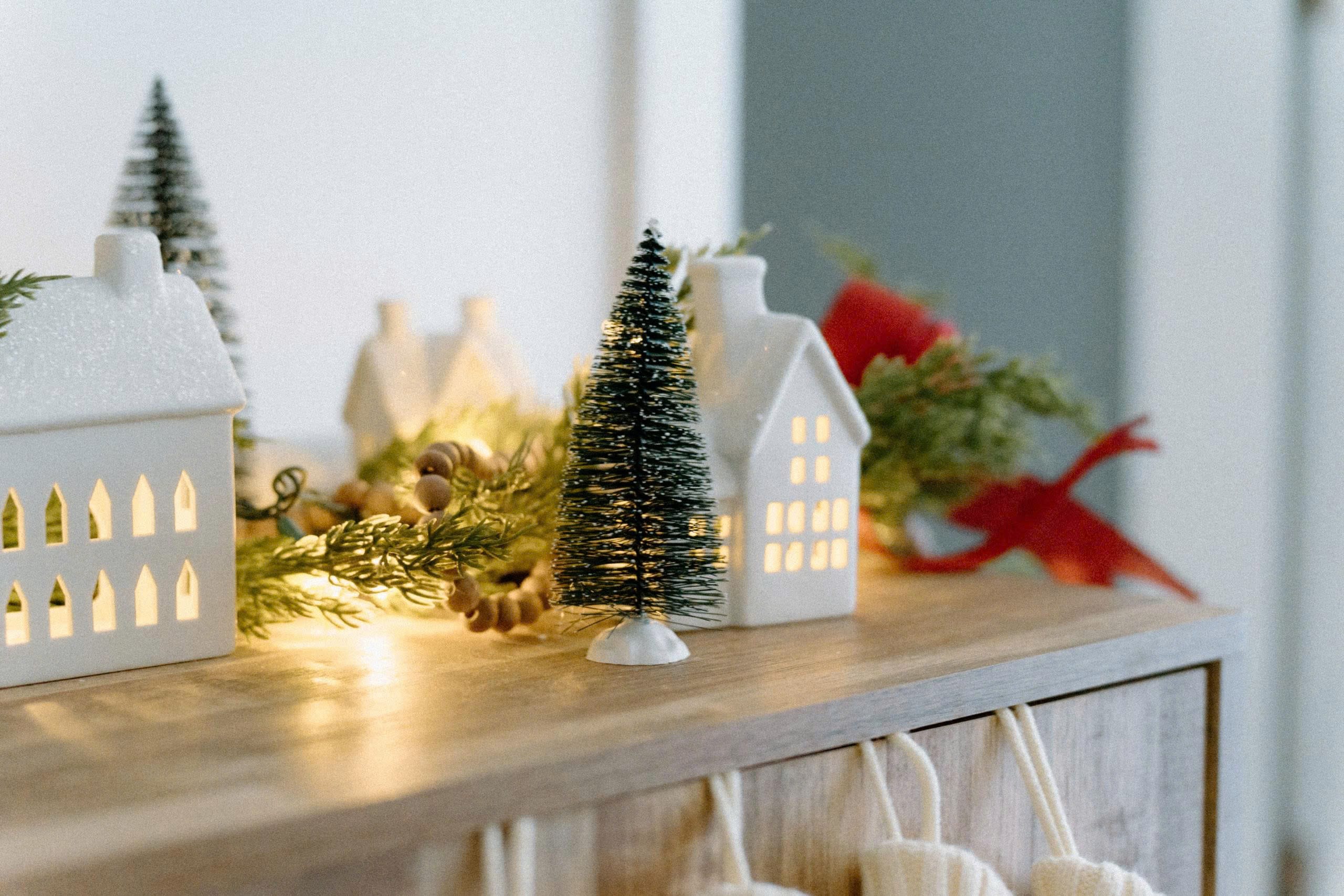 Mantel styled to the 2026 holiday home decor trends, with lit ceramic houses grouped to one side